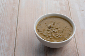 Mung beans porridge (bubur kacang hijau) is a Malaysian traditional dish usually eat as starter or desert. Made from mung beans, coconut milk & palm sugar. Isolated over wooden background.