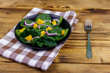Tasty salad with spinach, orange, red onion and sesame seeds on wooden table. Healthy food or vegetarian concept