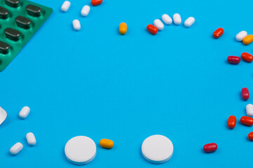 Scattered pills and medicines in blisters on a blue background copy space.