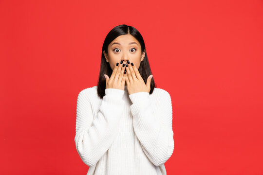 Shocked Asian Woman Covering Mouth With Hands Isolated On Red