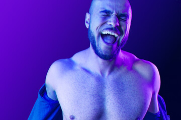 Young black man takes off the shirt in neon light