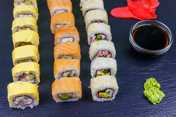 Set of sushi rolls on a black stone slate