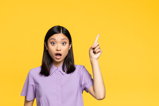 Shocked Asian Woman With Open Mouth Pointing With Finger Isolated On Yellow