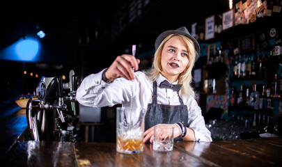 Girl barman makes a cocktail in the taproom