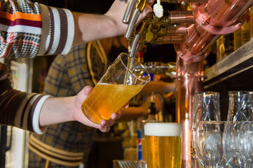 Beer is pouring from the tap into the glass. At the beer bar.