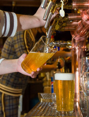Beer is pouring from the tap into the glass. At the beer bar.