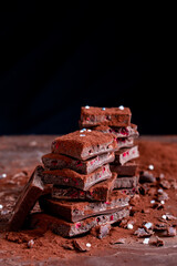 Organic food snack tasty sweet dessert milk dark chocolate bar macro closeup broken slide piece and fruit orange raspberry hazelnut nuts on cocoa cacao powder wooden table for new year Christmas gift