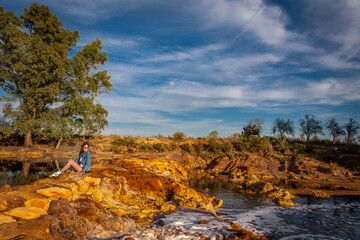beautiful landscape of a river with trees, orange stones and reflection in the water
