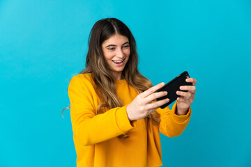 Young caucasian woman isolated on blue background playing with the mobile phone