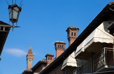 Fototapeta na wymiar Row of different stone chimneys on the roof of an Italian house, Italy