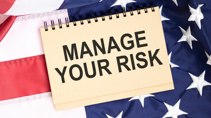 Fototapeta na wymiar Notepad with text MANAGE YOUR RISK on the American flag.