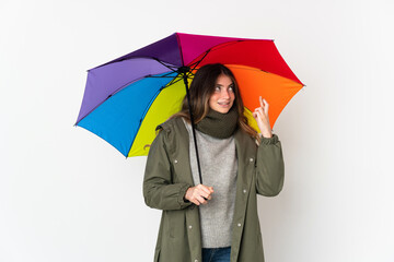 Young caucasian woman holding an umbrella isolated on white background with fingers crossing and wishing the best