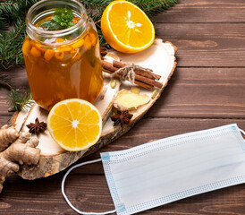 A healthy drink from sea buckthorn on a wooden table. Medical mask and sea buckthorn drink.