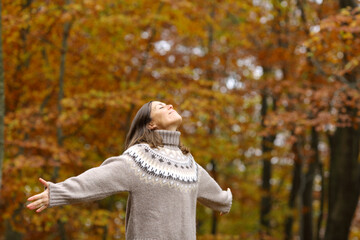 Middle age woman stretching arms in a forest in autumn