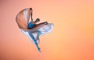 Ballerina in a light light dress flying in jump on an illuminated colored background - obrazy, fototapety, plakaty