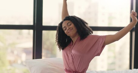 Lazy morning. Young well slept african american woman in pajamas stretching, sitting in bed, waking up
