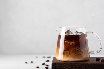 small coffee pot with ice coffee and milk on a light background