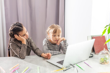 two little sad girls study online with a laptop
