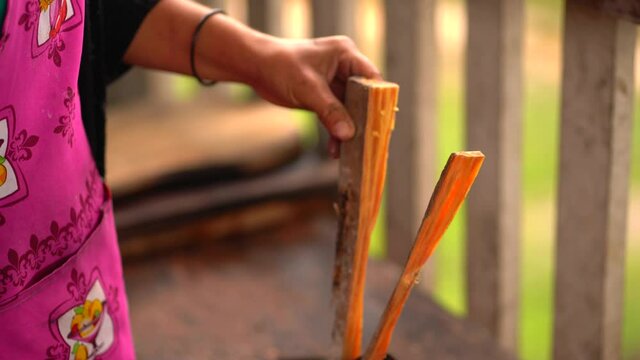 Woman  chopping wood. Woman using face mask in rural kitchen