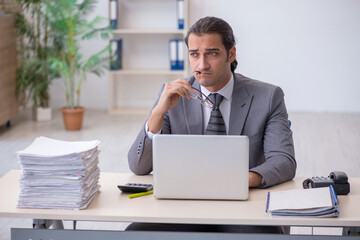 Young male employee unhappy with excessive work in the office