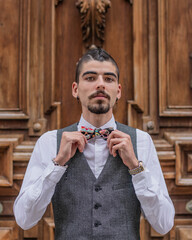 Chico con pajarita. Modelo en traje. Poniéndose una pajarita.