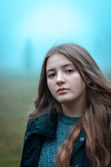Fototapeta premium young woman with long blonde hair and black hut at foggy autumn day 