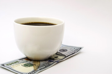 On the hundred dollar bill is a white Cup of black coffee.