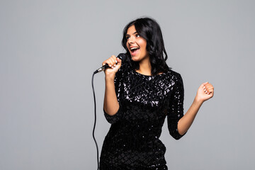 Elegant female singer singing on microphone isolated on gray background
