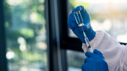 The vaccination tube was in the hand of a young chemist working in a hospital room and a blue glove.