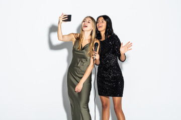 life style, happiness, emotional and people concept. Two beauty women with a microphone singing and make selfie