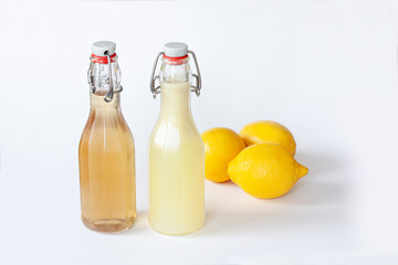 Two flip-top patent closure bottles with homemade lemon syrup or juice and three lemons on white background.