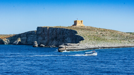 The small island of Comino sits between Malta and Gozo. Also seen is St. Mary's Tower also known as...