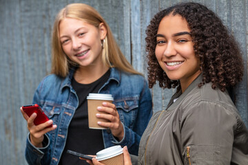 Interracial Mixed Race Girl Teenagers Using Smart Phones Drinking Coffee