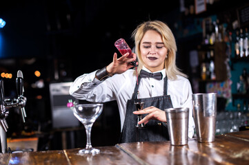 Confident woman bartender decorates colorful concoction