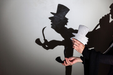 play shadow projected against a white background. a old man with hat.