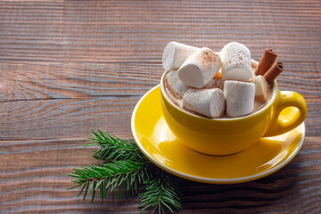Christmas cup of coffee with marshmallows and cinnamon on wooden background. Copy space.