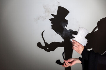 play shadow projected against a white background. a old man with hat.