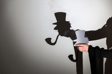 play shadow projected against a white background. a old man with hat.