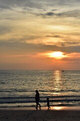 silhouette of a person on the beach when sunset ,orange sky and reflection