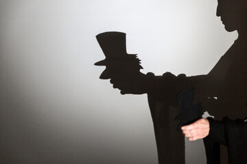 play shadow projected against a white background. a old man with hat.