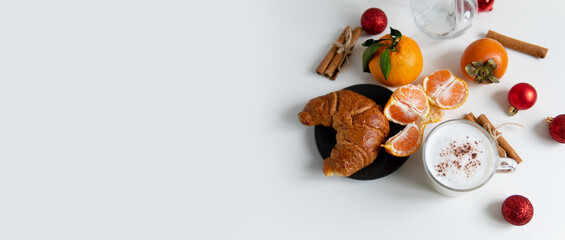 Composition with New Year's assortments on a white table. Christmas mood. on a white background coffee croissant tangerines and Christmas red balls. Free space for the layout.