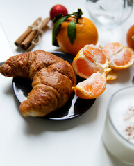 Composition with New Year's assortments on a white table. Christmas mood. on a white background coffee croissant tangerines and Christmas red balls. Free space for the layout.