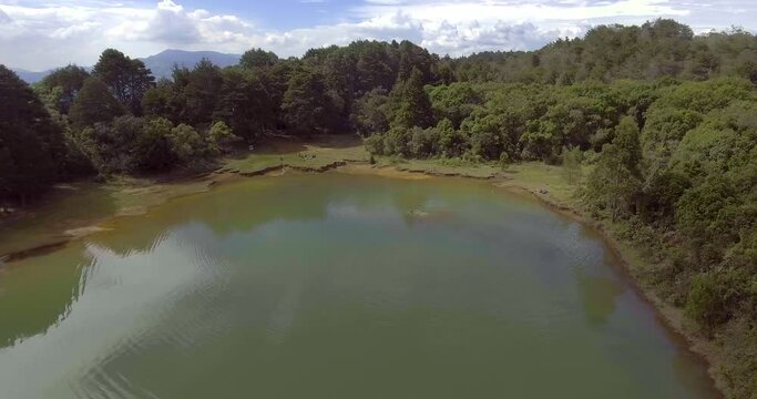 Pristine Green Guarne Lagoon in the Middle of the Woods near Medellin, Colombia on a Cloudy Day shot from in Smooth Travelling form Above