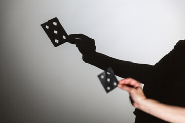 play shadow projected against a white background, a magic card trick