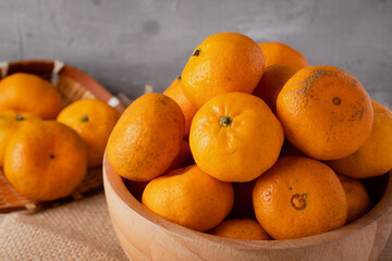 Tangerines in wooden bowls on gray background