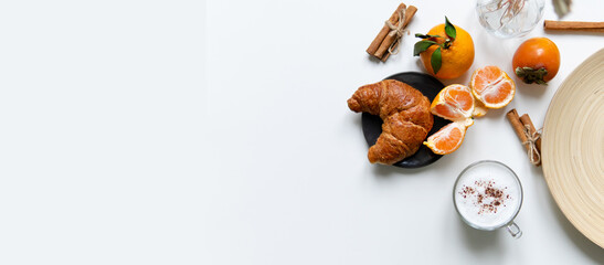 Composition with New Year's assortments on a white table. Christmas mood. over white background coffee croissant tangerines and cinnamon. Place for inscription layout. Flat lay