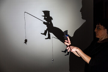 play shadow projected against a white background. a homeless man with a rod fishing