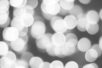 Black and white blurred picture of Christmas lights, monochromatic abstract background.