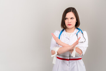 Portrait of beautiful young doctor says no on light background