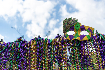 iron fence covered with Mardi Gras beads topped with mask